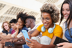 photo of several Gen Z-aged people looking at their cell phones